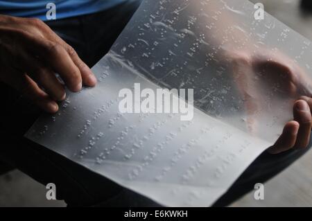 Blind man reading from a page written in braille Stock Photo