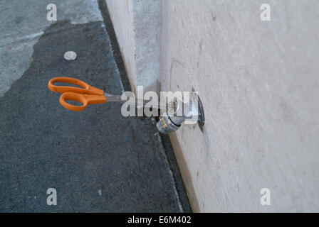 Scissors used as a handle to control water tap. Stock Photo