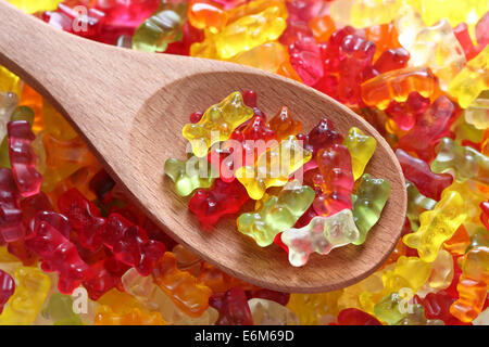 Gummy bears on a wooden spoon on a gummy bear background. Closeup. Stock Photo