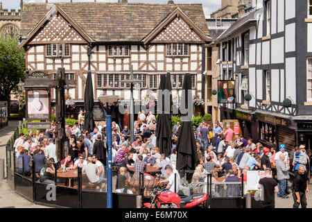 Sinclair's Oyster Bar and 16thc timbered The Old Wellington Inn with crowds of people in busy beer garden outside. Manchester UK Stock Photo