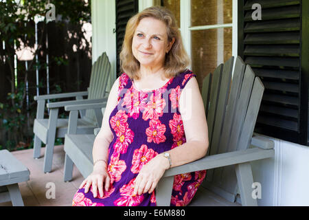 Woman sitting outside house Stock Photo