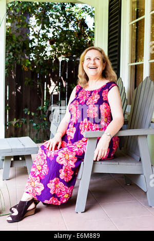 Woman sitting outside house Stock Photo