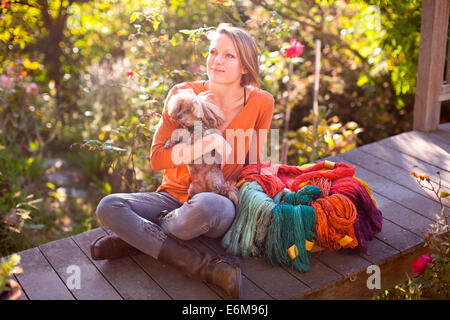 Woman sitting in garden with dog Stock Photo