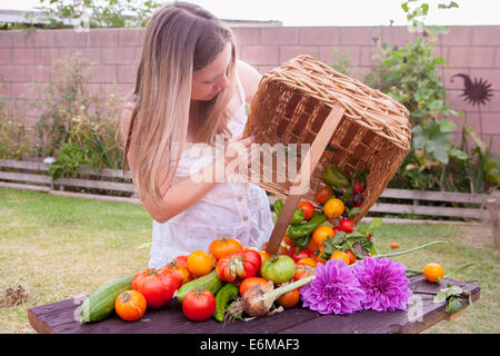 View of woman in garden with basket of vegetables Stock Photo