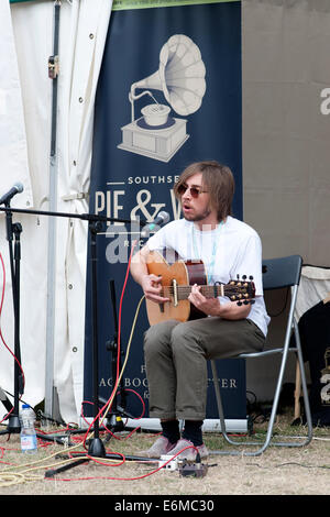 a young male sings and plays an acoustic guitar at a stall at the victorious festival 2014 southsea england uk Stock Photo