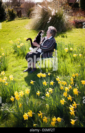 Pensioner with pet black and white cat in her Spring garden. Stock Photo