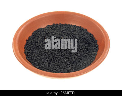 A small clay bowl with a portion of black caraway seeds on a white background. Stock Photo