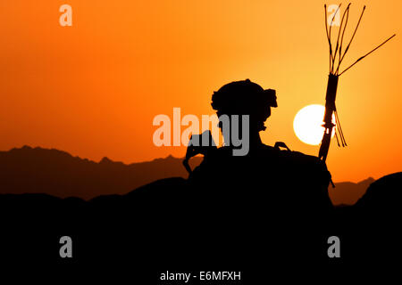 A US Army soldier is silhouetted by the setting sun while on combat patrol August 18, 2014 in Morghan Kachah, Kandahar Province, Afghanistan. Stock Photo