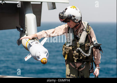 A US Navy fighter pilot checks laser guided bombs during a pre-flight check on an F/A-18C Hornet before launching a mission from the aircraft carrier USS George H.W. Bush August 23, 2014 in the Arabian Gulf. The pilots are flying targeted airstrikes against extremists known as the Islamic State in Iraq and the Levant. Stock Photo