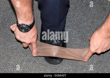 An RCMP cadet makes sure his boots are always shiny, using a strip of pantyhose which he carries with him in his hat. Stock Photo