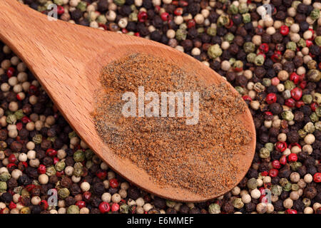 Ground mixed pepper in a wooden on a mixed peppercorn background. Stock Photo
