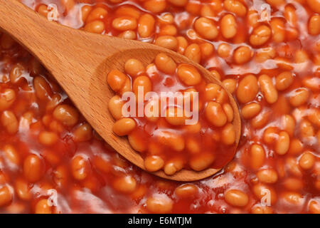 Baked beans in tomato sauce in a wooden spoon. Stock Photo