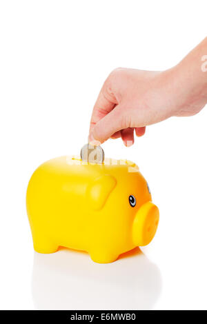 Yellow piggy bank is getting two euro coin from a hand on white background Stock Photo