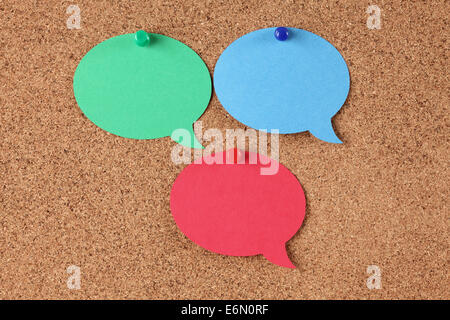 Blank green, blue and red speech bubbles on corkboard (bulletin board). Stock Photo