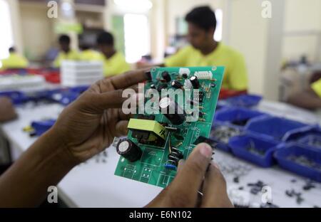 Dhaka, 2014. An employee works on a mother board of a solar optimizer, a key component of solar home systems in Solaric factory in Dhaka. mother board Stock Photo