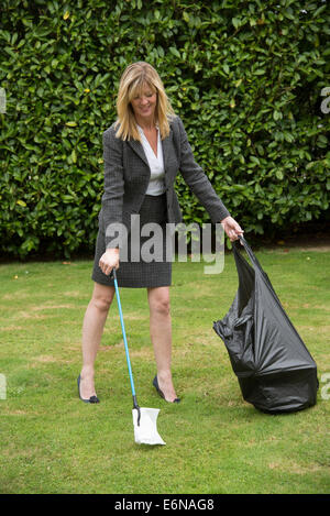 Woman litter picking with a black plastic sack wearing a business style suit Stock Photo