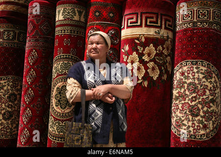 Uzbek woman visits a carpet market in Urgench, Uzbekistan. Stock Photo