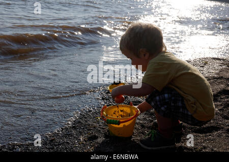 A young boy playing with a bucket and spade on the beach Plage Jacques Cartier, Quebec on the St Lawrence shoreline Stock Photo