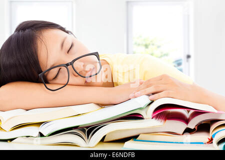 tired student girl with glasses sleeping on the books with room background Stock Photo