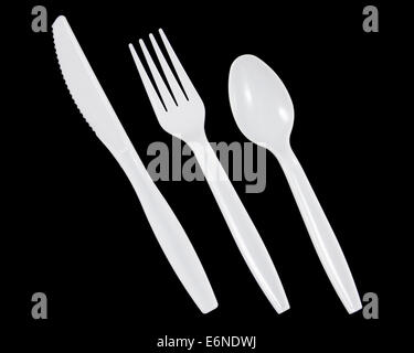 White plastic knife, fork and spoon on black background. Stock Photo