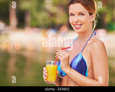 Young woman in bikini with juice looking at camera and smiling Stock Photo