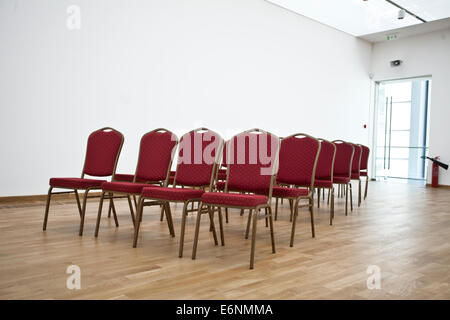 Red chairs in empty conference hall with laminate. Stock Photo