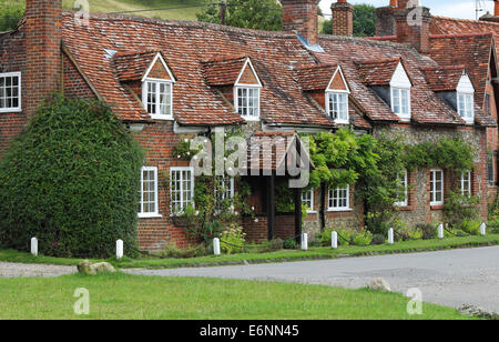 Traditional English Village brick and flint Cottage with Climbing plants on the Wall Stock Photo