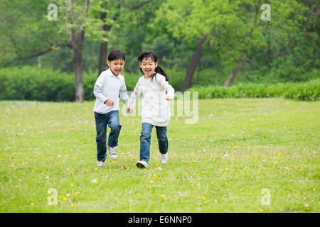 Happy children holding hands running on the grass Stock Photo - Alamy