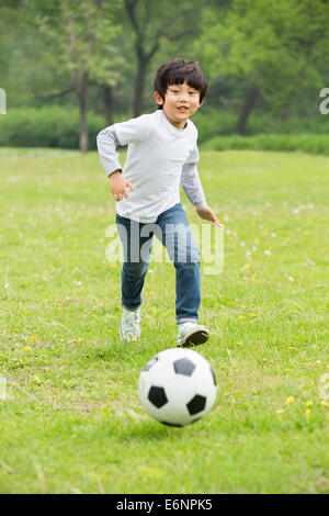 Happy boy playing football on the grass Stock Photo