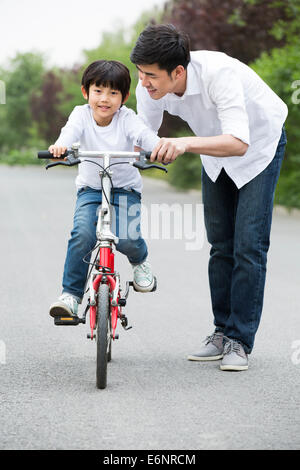 Father teaching son to ride a bicycle Stock Photo