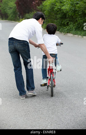 Father teaching son to ride a bicycle Stock Photo