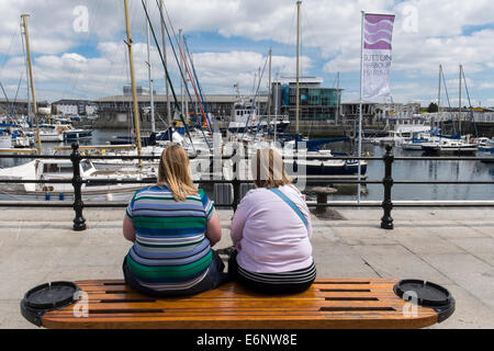 Two overweight women sitting on a bench on Plymouth Barbican, Plymouth, Devon, England, UK Stock Photo