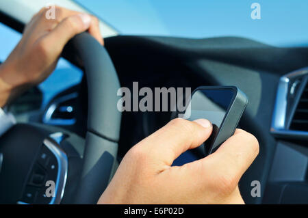 closeup of a man using a smartphone while driving a car Stock Photo