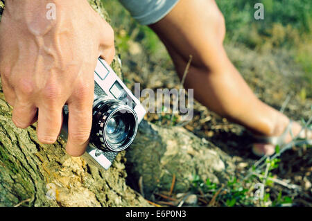 closeup of a young man lying on a tree holding an old camera in his hand Stock Photo