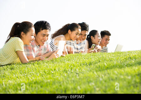 Cheerful young adults lying down on grass playing together Stock Photo