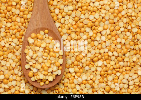 Split yellow peas in a wooden spoon on split yellow peas background. Stock Photo