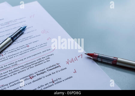 Blue and red pens sit on a manuscript proof page, during a break in proofreading. Stock Photo