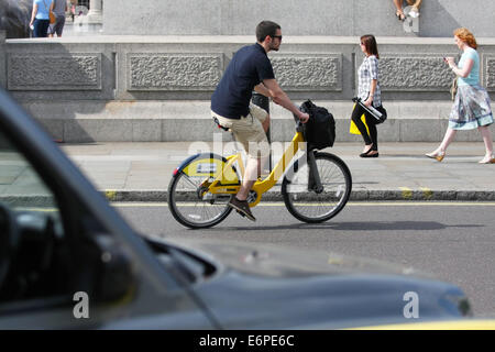 A cyclist and car traveling around a roundabout in Trafalgar Square, London Stock Photo