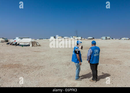 Two UNHCR employees discuss work at Za'atari (Zaatari) camp for Syrian refugees, in northern Jordan, under a clear blue sky. Stock Photo