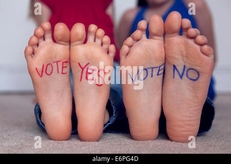 Red 'vote yes' and blue 'vote no', written on children's feet. Conceptual 'to vote with your feet'. Stock Photo