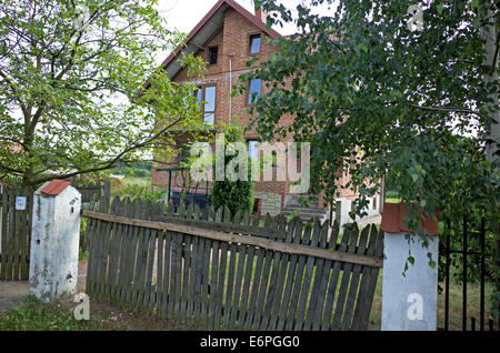Modern Polish house behind an old wooden picket fence. Rzeczyca Poland Stock Photo