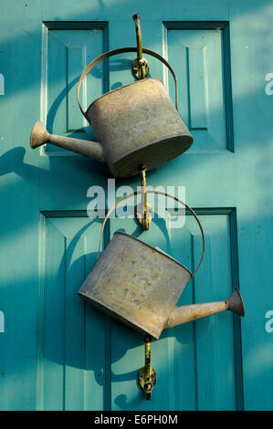 Two metal watering cans hanging on a wooden door in Steveston Village, Richmond, BC, Canada Stock Photo