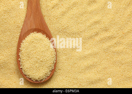 Couscous in a wooden spoon on couscous background. Close-up. Stock Photo