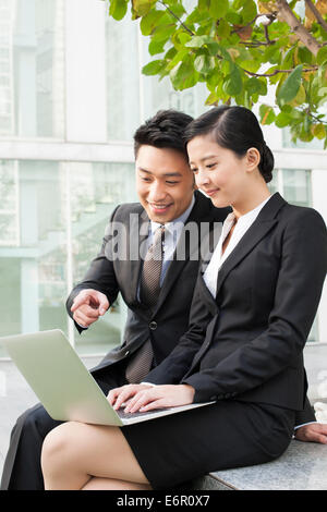 Happy young business partners using laptop outdoors Stock Photo