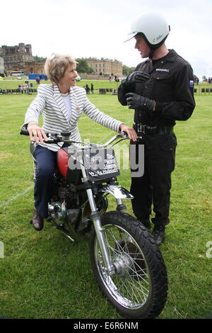 Peak District, Derbyshire, UK.  29 August 2014. The Duchess of Devonshire tries out a 750cc Triumph motorcycle belonging to The Royal Signals White Helmets Motorcycle Display Team as she chats to its usual rider, Team Sergeant Stevie Marshall  during the first day of the annual Chatsworth County Fair held in the parkland surrounding  the Derbyshire stately home.  The three day event runs until Sunday 31 August. Credit:  Matthew Taylor/Alamy Live News Stock Photo
