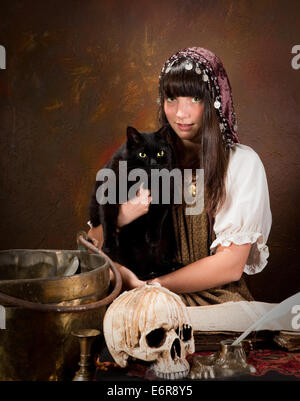 Halloween witch holding her black cat with green eyes (the book is 300 years old, no copyright problems) Stock Photo