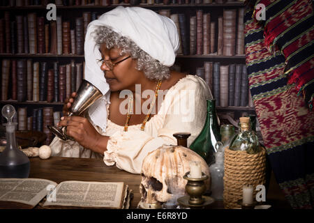 Dark alchemist tasting a brew from her laboratory Stock Photo