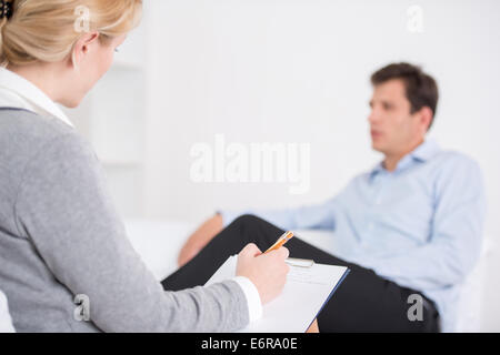 Female psychologist making notes during psychological therapy session Stock Photo