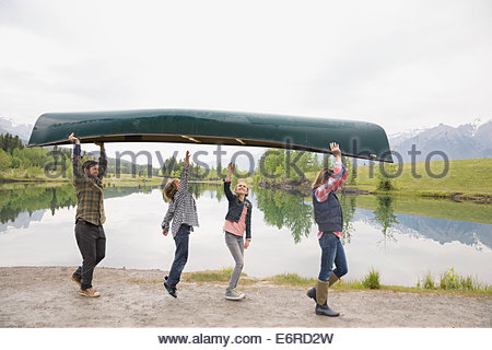 Family carrying canoe by still lake
