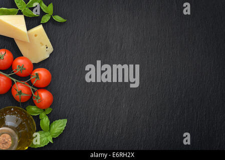 Ingredients of italian cuisine  - cherry tomato, basil, parmesan and olive oil - on dark background Stock Photo